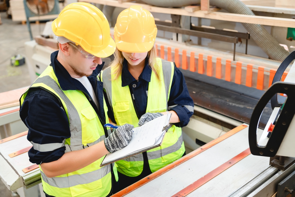 Factory Colleagues In Conversation While Examining Production